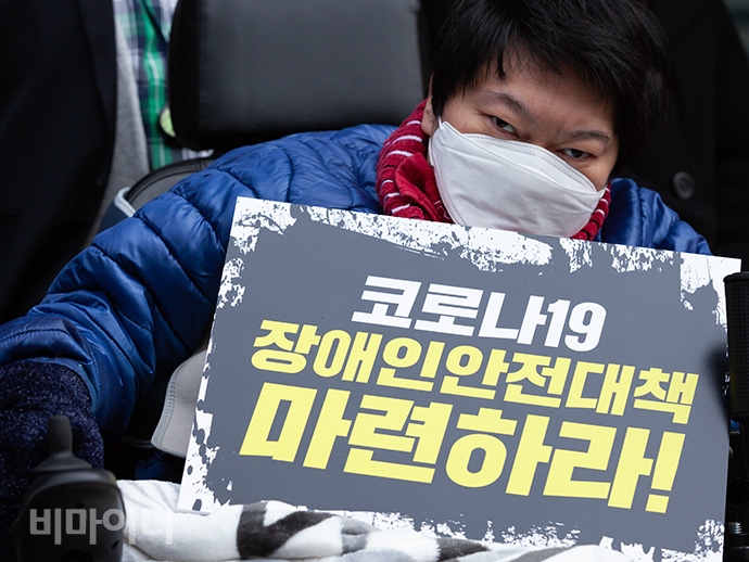 이상우 장애인 활동가가 하얀 마스크를 쓰고 ‘코로나19 장애인안전대책 마련하라’라고 적힌 손팻말을 들고 있다. 사진 박승원