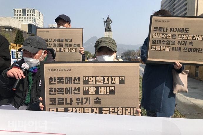 기자회견 참가자가 ‘한쪽에선 외출 자제, 한쪽에선 방 빼! 코로나 위기 속 모든 강제퇴거 중단하라’, ‘코로나 위기에도 임대수입은 신성불가침? 임대수입은 위기 속 고통분담 위해 쓰여야 한다’ 등의 손팻말을 들고 있다. 사진 허현덕