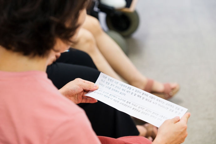 ‘질병과 함께 춤을’에서 진행한 연극 워크숍에서 발표하는 나의 모습. 나의 심정을 담은 종이에는 ‘내 질병을 사람들에게 밝힐 수 없어 창피하다’는 내용이 쓰여 있다. 나는 사람들에게 밝은 척 연기하며 살았고 힘든 부분을 애써 숨기며 살아왔다. 사진 혜영