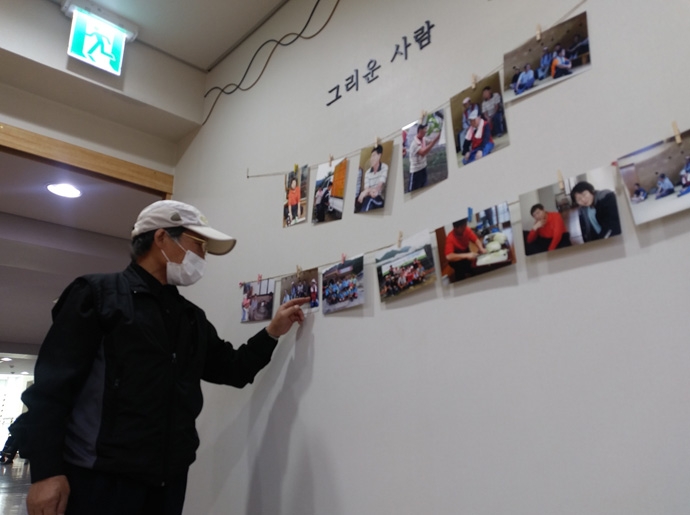 한 홈리스 무연고자의 생전 사진을 보고 설명하고 있는 지인. 사진 나눔과나눔