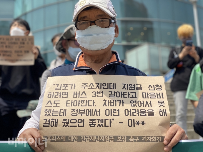 서울역 앞에서 한 활동가가 ‘김포가 주소지인데 지원금 신청하려면 버스 3번 갈아타고 마을버스도 타야한다. 차비가 없어서 못했는데 정부에서 이런 어려움을 해결해 줬으면 좋겠다’라고 적힌 피켓을 들고 있다. 사진 이가연