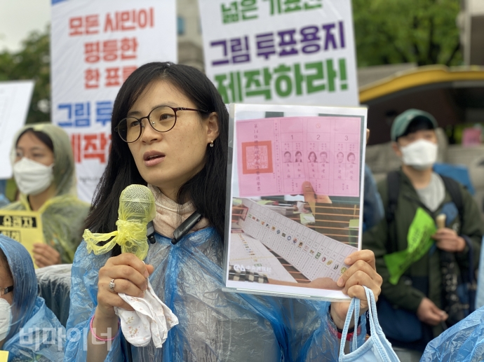 19일, 경기도 과천시 중앙선거관리위원회 앞에서 ‘장애인참정권 확보를 위한 대응팀’이 21대 국회의원 선거뿐 아니라 되풀이되는 장애인의 참정권 침해에 대한 대책 마련을 요구하며 항의 방문 기자회견을 열었다. 김예원 장애인권법센터 변호사가 대만의 그림투표용지 사진을 들고 발언을 하고 있다. 사진 이가연