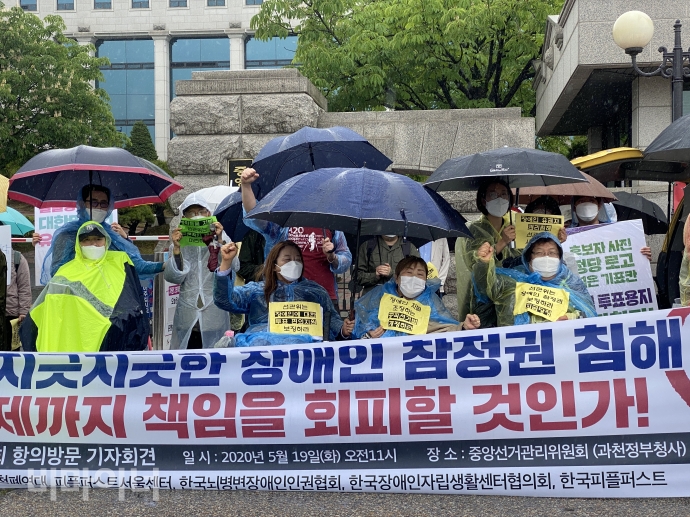 비가 오는 궂은 날씨 속에 참가자들이 기자회견에 참여해 중앙선거관리위원회 앞에서 피켓을 들고 구호를 외치고 있다. 사진 이가연