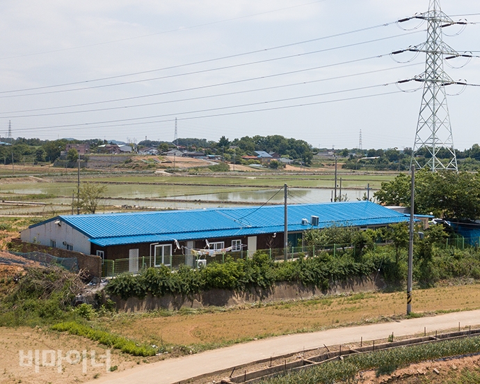 장애인 사망 사건이 발생한 미신고시설 평강타운과 개인운영시설 사랑의집이 파란색 한 지붕 아래 있는 모습. 그 옆에는 커다란 송전탑 하나가 세워져 있다. 사진 박승원
