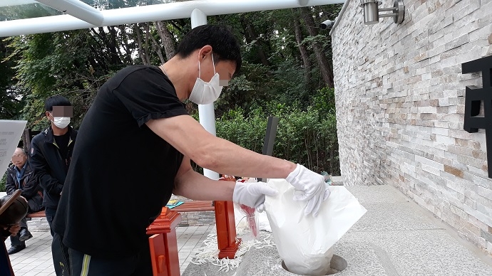 다섯 살에 헤어진 아버지의 무연고장례에서 유골을 뿌리고 있는 아들. 나눔과나눔