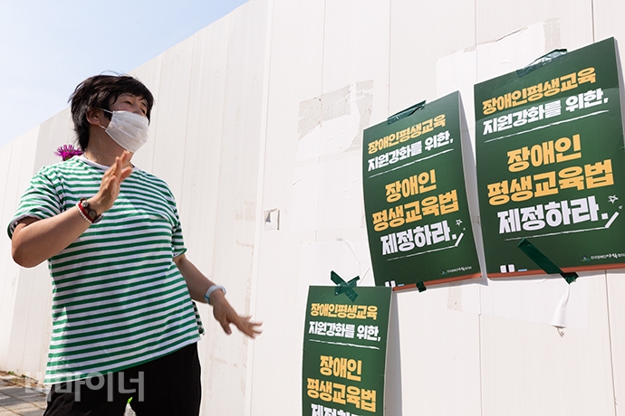 박성숙 노들장애인야간학교 학생이 ‘노들 테크노 전사’의 테크노 반주에 맞춰 춤추고 있다. 그 뒤에는 ‘장애인 평생교육법 제정하라’라고 적힌 손팻말이 벽에 붙어있다. 사진 박승원