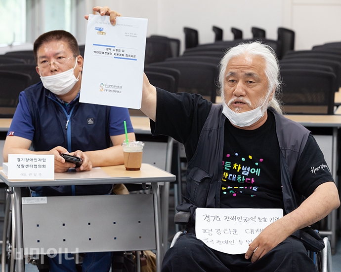 박경석 전국장애인야학협의회 이사장이 권달주 경기장애인자립생활센터협의회 대표 앞에 놓인 ‘평택 사랑의 집 학대피해장애인 지원계획 회의자료’를 들고 “이 회의에 문제를 제기하러 왔습니다. 경기도와 평택시는 즉각 탈시설 계획을 수립하고 장애인수용시설 신규입소 금지해야 합니다”라고 외쳤다. 사진 박승원