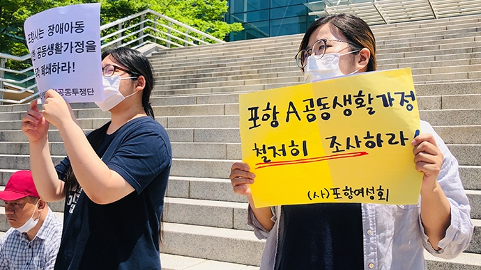 포항여성회 회원이 ‘포항 A 공동생활가정 철저히 조사하라!’라고 적힌 손팻말을 들고 있다. 사진 경북장애인차별철폐연대(준) 제공