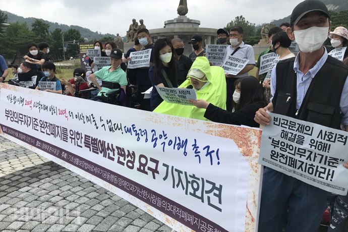 빈곤사회연대가 25일 오전 11시 30분 청와대 사랑채 앞에서 오는 8월에 발표될 제2차 기초생활종합계획(2021~2023)에 부양의무자기준 완전 폐지 계획을 밝히고, 이에 따른 특별예산을 편성 촉구 기자회견을 열었다. 기자회견 참가자가 ‘빈곤문제의 사회적 해결을 위해! 부양의무자기준 완전 폐지하라’라는 손팻말을 들고 있다. 사진 허현덕  