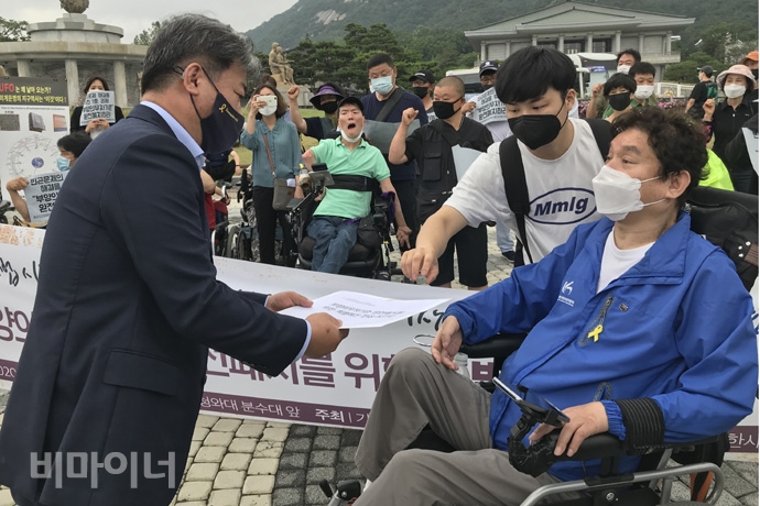 청와대 시민사회수석실에 최용기 한국장애인자립생활센터협의회 회장이 ‘부양의무자기준 완전 폐지를 위한 특별예산 편성 요구안’을 전달하며, 당부의 말을 전하고 있다. 사진 허현덕 