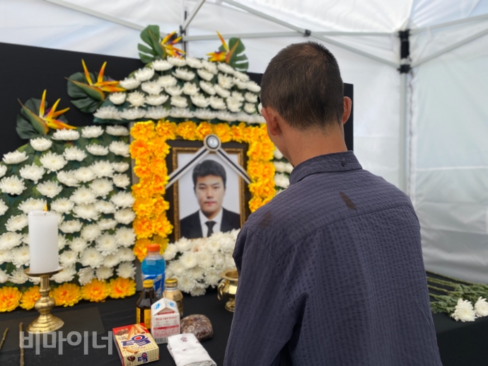 고 김재순 장애인 노동자의 아버지 김무영(가명) 씨가 전남 광주 고용노동청 앞에 마련된 분향소를 정리하고 있다. 김재순의 영정사진 앞에는 방문객들이 두고간 음료와 과자들이 놓여있다. 사진 이가연