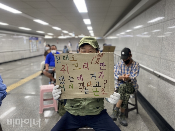 지난 6월 29일 홈리스행동은 서울역 연세빌딩 지하도에서 기자회견을 열어 서울시의 ‘홈리스 쪼개기 고용’ 개편안의 전면 철회와 공공일자리 전면 확대를 촉구했다. 이날 홈리스 활동가가 ‘원래도 쥐꼬리만 했는데 거기서 더 깎는다고?’라고 적힌 손팻말을 들고 있다. 사진 이가연 