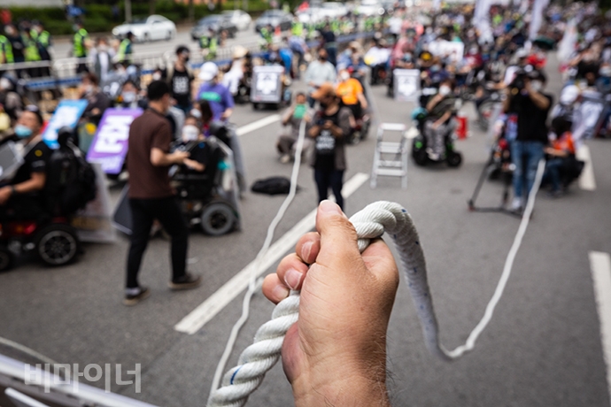 박경석 전국장애인야학협의회 이사장이 연대의 끈이라며 밧줄을 집어 들었다. 장애등급제 '진짜' 폐지 집회에 참여한 장애인활동가들은 반대쪽 끈을 맞잡았다. 사진 박승원