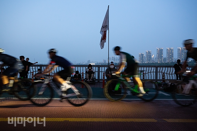 저녁 8시가 되자 하늘이 어둑어둑해지기 시작했다. 잠수교 가장자리에서 쉬고 있는 장애인 활동가들. 그 앞으로 자전거를 탄 사람들이 지나가고 있다. 사진 박승원