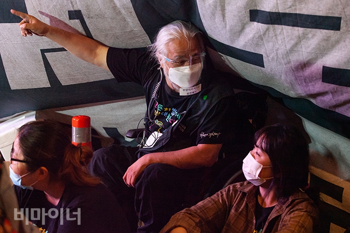 문화행사를 지켜보던 박경석 이사장이 현수막에 파묻힌 채 한 활동가와 이야기를 나누고 있다. 사진 박승원
