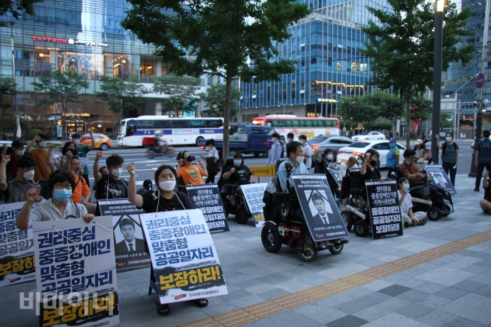 결의대회에 참석한 사람들이 손을 들고 구호를 외치고 있다. 피켓에는 ‘권리중심의 중증장애인 맞춤형 공공일자리 보장하라’라고 적혀있다. 사진 이가연