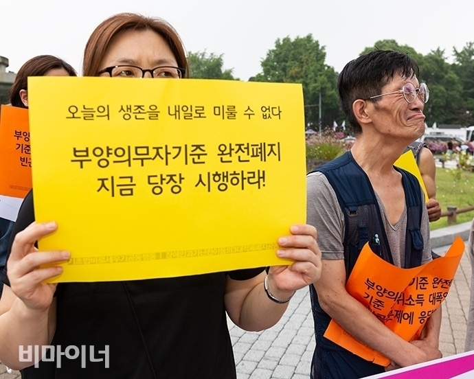 한 사람이 “오늘의 생존을 내일로 미룰 수 없다. 부양의무자 기준 완전 폐지 지금 당장 시행하라”고 적힌 손피켓을 들고 있다. 사진 박승원
