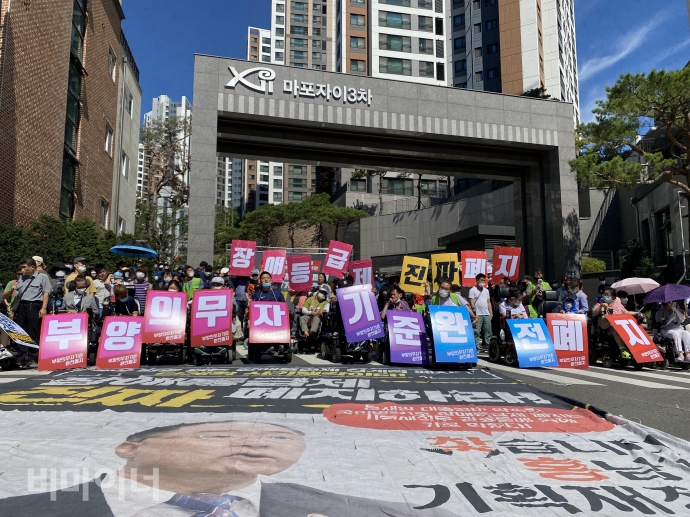 전국장애인차별철폐연대(아래 전장연)와 장애인과가난한사람들의 3대적폐폐지공동행동(아래 공동행동)은 15일 오후 2시, 홍남기 기획재정부 장관의 거주지 근방인 서울 마포아트센터에서 예산쟁취 투쟁결의대회를 열었다. 사진 이가연 전국장애인차별철폐연대(아래 전장연)와 장애인과가난한사람들의 3대적폐폐지공동행동(아래 공동행동)은 15일 오후 2시, 홍남기 기획재정부 장관의 거주지 근방인 서울 마포아트센터에서 예산쟁취 투쟁결의대회를 열었다. 참가자들이 홍 장관이 거주하는 아파트 앞에서 결의를 다지고 있다. 사진 이가연