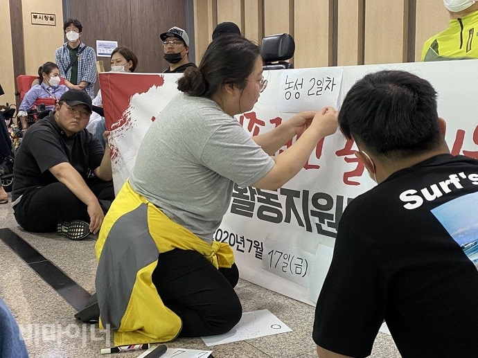 지난 17일 화성시장실 앞 농성장에서 조은별 경기장애인차별철폐연대 활동가가 ‘농성 2일 차’라고 쓴 종이를 붙이고 있다. 사진 이가연