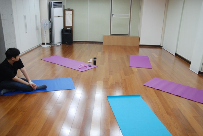연습실의 마룻바닥에 하늘색 요가 매트 2개와 보라색 요가 매트 3개가 놓여 있다. 왼쪽의 하늘색 요가 매트 위에 앉아서 양손으로 오른쪽 발목을 잡고 있는 안희제. 연습실의 붙박이장 옆으로는 에어컨과 선풍기, 스피커, 정육면체의 의자 4개가 놓여 있다. 제공 안희제 연습실의 마룻바닥에 하늘색 요가 매트 2개와 보라색 요가 매트 3개가 놓여 있다. 왼쪽의 하늘색 요가 매트 위에 앉아서 양손으로 오른쪽 발목을 잡고 있는 안희제. 연습실의 붙박이장 옆으로는 에어컨과 선풍기, 스피커, 정육면체의 의자 4개가 놓여 있다. 제공 다른몸들