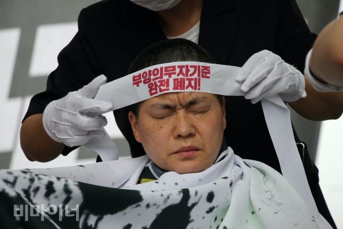 권은춘 충북장차연 대표가 삭발을 마치고 머리에 ‘부양의무자기준 완전폐지’라고 적힌 띠를 두르고 있다. 사진 이가연