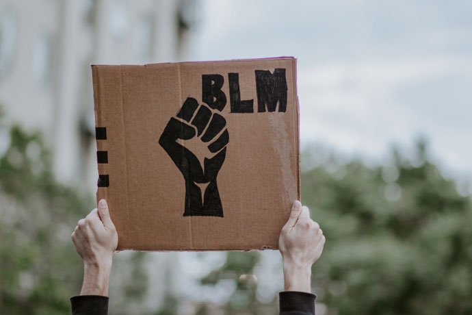 종이상자를 오려낸 듯한 갈색 골판지 종이에 주먹을 꽉 쥔 그림과 그 위에 BLM(Black lives matter) 문구가 쓰여 있다. 사진 언스플래시