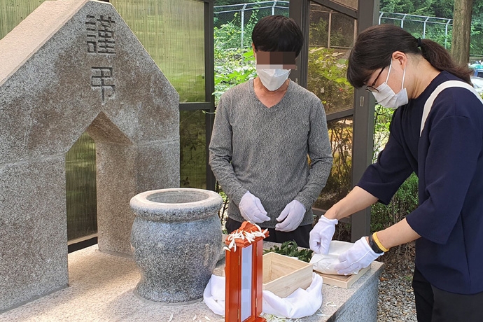 무연고 장례에서 형의 유골을 뿌리고 있는 동생. 사진 나눔과나눔