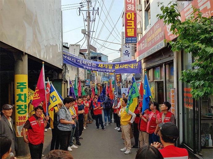 빈곤사회연대는 매월 ‘세’번째 ‘수’요일에 강제퇴거를 반대하는 세수문화제를 진행하고 있다. 2019년 5월에는 청계천·을지로에서 세수문화제를 했다. 세운정비촉진지구 3-2구역 골목에서 상인들이 “세입자 대책 없는 재개발 결사반대”라고 적힌 현수막과 깃발을 들고 서 있다. ⓒ빈곤사회연대 빈곤사회연대는 매월 ‘세’번째 ‘수’요일에 강제퇴거를 반대하는 세수문화제를 진행하고 있다. 2019년 5월에는 청계천·을지로에서 세수문화제를 했다. 세운정비촉진지구 3-2구역 골목에서 상인들이 “세입자 대책 없는 재개발 결사반대”라고 적힌 현수막과 깃발을 들고 서 있다. ⓒ빈곤사회연대