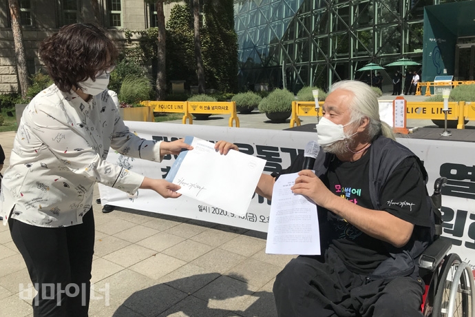박경석 전국장애인차별철폐연대 상임공동대표가 서울시장애인복지정책과 담당자에게 김순석 열사 동상·기념관 제안서를 전달하고 있다. 사진 허현덕 