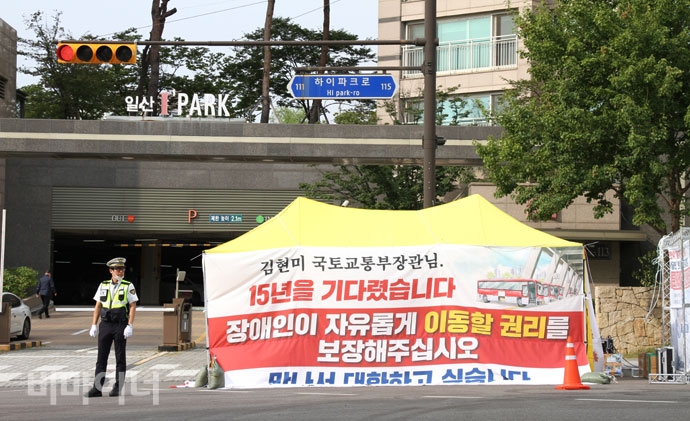 김현미 국토교통부 장관과의 면담을 촉구하며 전국장애인차별철폐연대는 29일 김 장관의 집 앞에 천막을 설치했다. 천막에는 “김현미 국토교통부 장관님, 15년을 기다렸습니다. 장애인이 자유롭게 이동할 권리를 보장해주십시오. 만나서 대화하고 싶습니다”라는 글자가 써진 커다란 현수막이 걸려 있다. 사진 강혜민