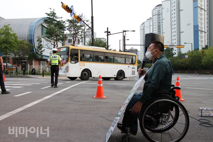 결의대회를 하는 장애인들 곁으로 휠체어 탄 장애인은 탑승할 수 없는 버스가 지나가고 있다. 사진 강혜민 