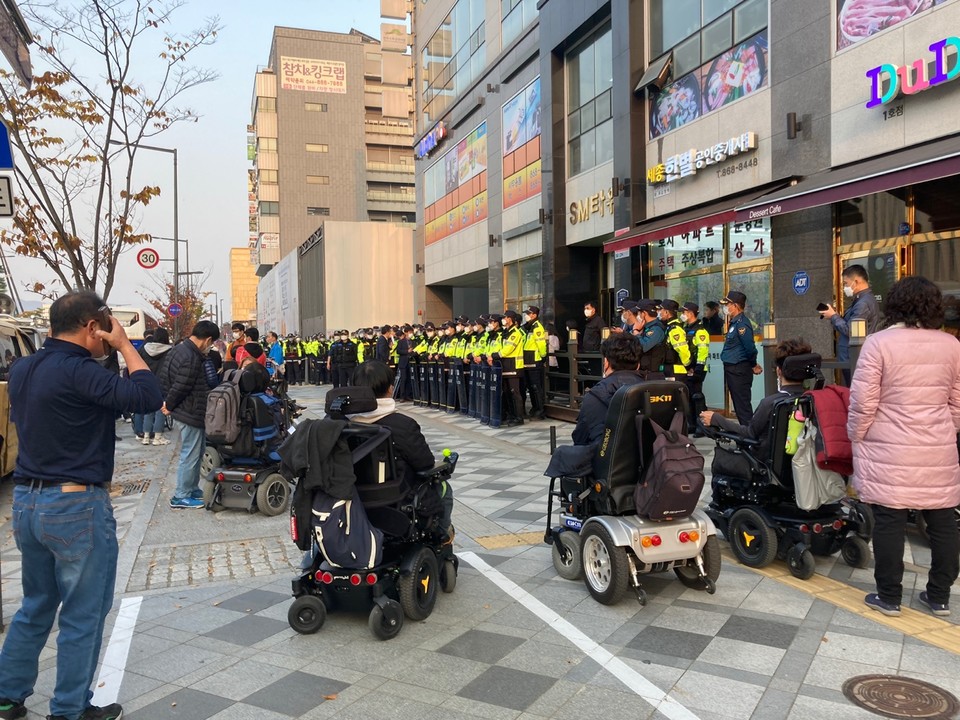 장애인들이 점거하고 있는 세종시청을 에워싸고 있는 수십 명의 경찰들과 항의 집회를 하고 있는 장애인활동가들. 사진 전국장애인차별철폐연대 