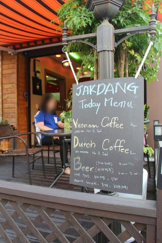 2014년 안산의 원곡동에서 카페 ‘작당’을 운영한 적 있다. 야트막한 카페 울타리 위에 큰 글씨로 ‘작당’이영어로 적혀 있고 그 너머 야외 카페 테라스에 손님이 앉아 있다. ⓒ정혜실