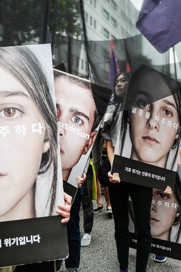사람들이 “멸종을 마주하다. 기후위기는 인류의 위기입니다.”라고 적힌 손피켓을 들고 있다. 사진 최인기