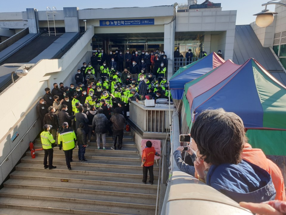 노량진역 2번 출구 앞 계단에 동작경찰서 경찰이 모여 있다. 물대포와 소화기를 맞은 연대인이 육교 위에서 경찰을 바라보고 있다. 사진 옥바라지선교센터