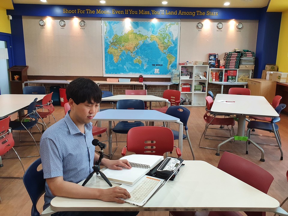 김헌용 교사가 원격수업 촬영을 위하여 구룡중학교 영어 교과실에서 수업을 준비하고 있다. 그의 앞에는 노트북과 함께 점자정보단말기가 놓여 있다.  ⓒ김헌용