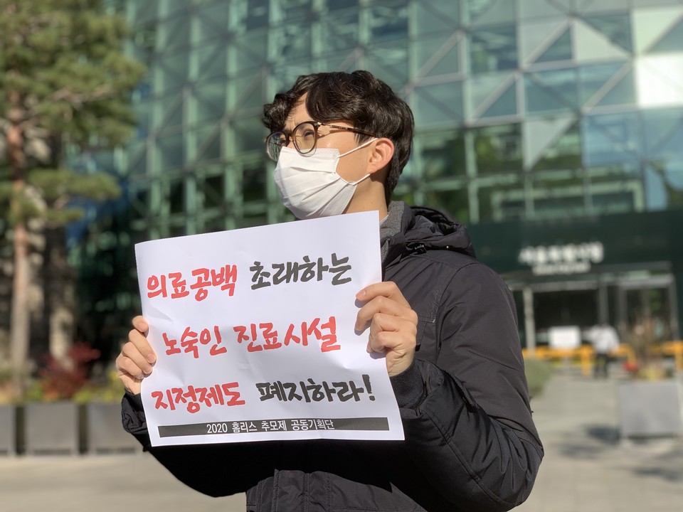 전진한 인도주의실천의사협의회 정책국장이 '의료 공백 초래하는 노숙인 진료시설 지정 제도 폐지하라!'라고 적힌 피켓을 들고 있다. ⓒ빈곤사회연대