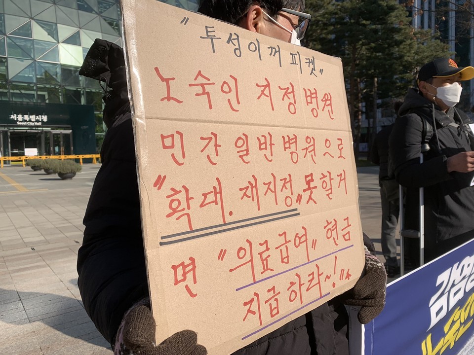 홈리스야학 학생이 재활용 박스로 만든 피켓을 들고 기자회견에 참석했다. 피켓에는 '투성이꺼 피켓. 노숙인 지정 병원, 민간 일반 병원으로 확대, 재지정 못할 거면 의료급여 현금 지급하라~!'라고 적혀 있다. ⓒ빈곤사회연대