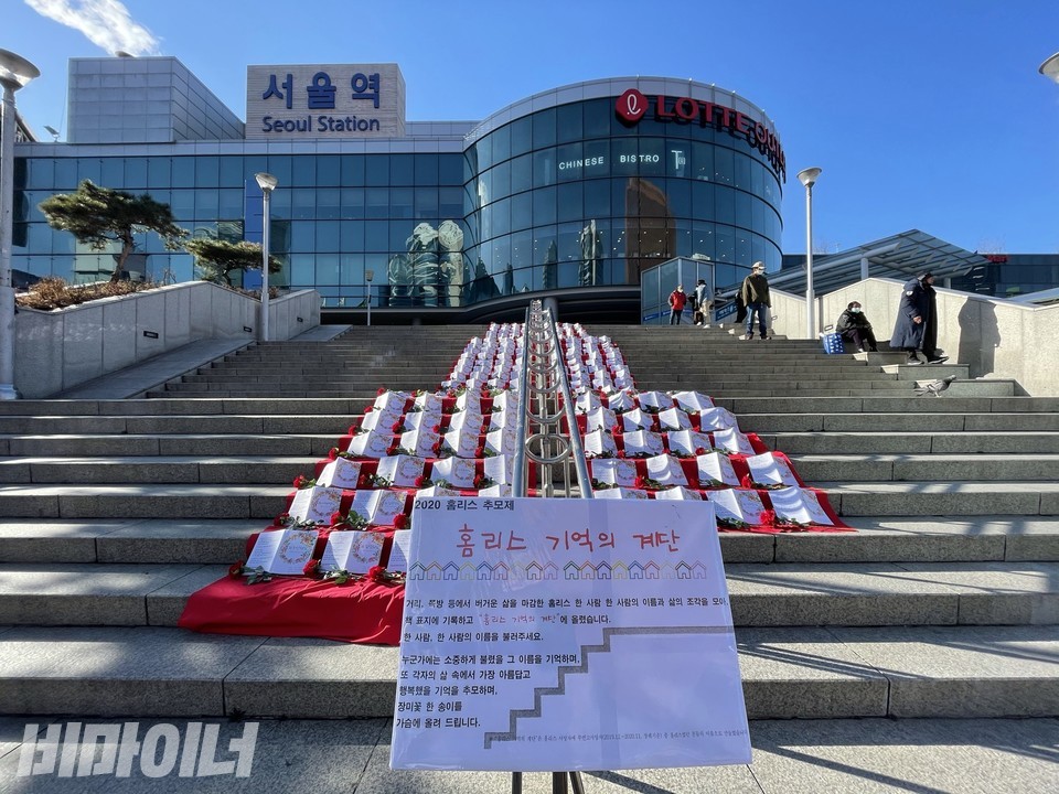 ​서울역 광장 계단에 홈리스 사망자 295명을 추모하는 '홈리스 기억의 계단'이 설치돼 있다. 빨간 레드카펫 위에 홈리스 이름이 적힌 책 295권과 장미꽃이 놓여 있다. 사진 하민지