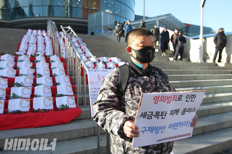 기자회견 참석자가 '명의범죄로 인한 세금폭탄 피해 홈리스 구제방안 마련하라!'라고 적힌 피켓을 들고 있다. 사진 하민지