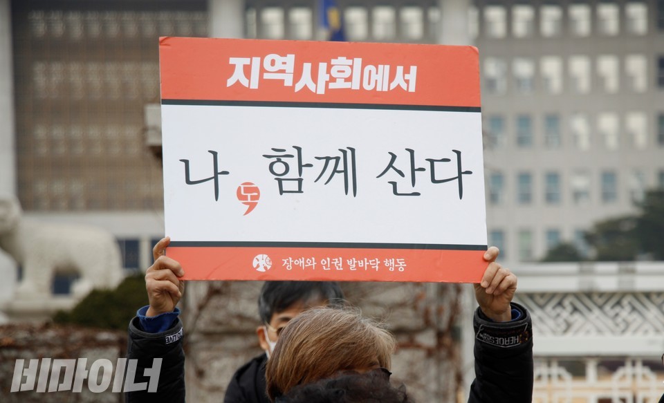 12월 10일 세계 인권의날, 최혜영 더불어민주당 의원, 장혜영 정의당 의원을 비롯한 68명이 공동으로 장애인 탈시설지원법안을 발의했다. 장애계는 환영의 뜻을 내비치며, 오전 국회 앞에서 기자회견을 열었다. 참가자가 ‘지역사회에서 나(도), 함께 산다’라는 손팻말을 들고 있다. 사진 허현덕 