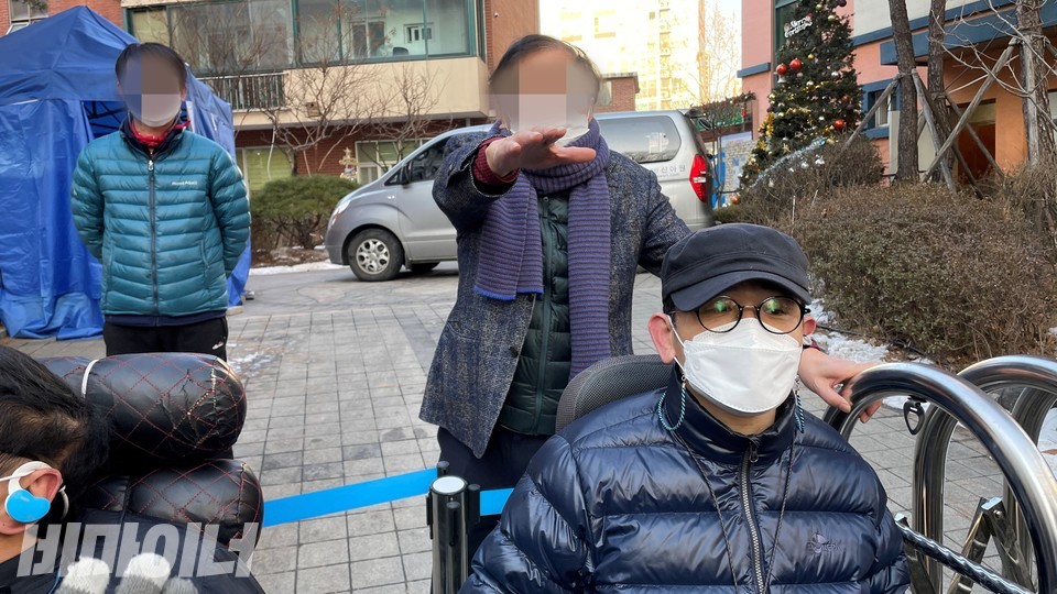 황 아무개 신아원 원장이 오른손을 뻗고 "찍지 마세요. 초상권이 있습니다"라고 말하며 기자의 촬영을 제지하고 있다. 황 원장 왼쪽에 푸른 점퍼를 입고 있는 사람은 신아원 시설과장이다. 사진 하민지