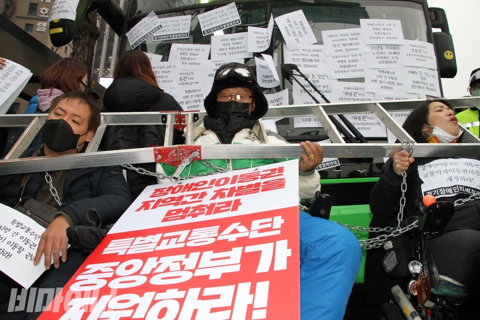 22일 오후 3시 전장연 등은 서울역 7번 버스정류장에서 장애인 이동권 완전 쟁취를 외치며 ‘버스 타기 직접행동’을 했다.  저상버스를 타고 서울 프레스센터에 내린 세 장애인 활동가들이 사다리를 목에 매고  버스를 가로 막고 있다. 사진 이가연