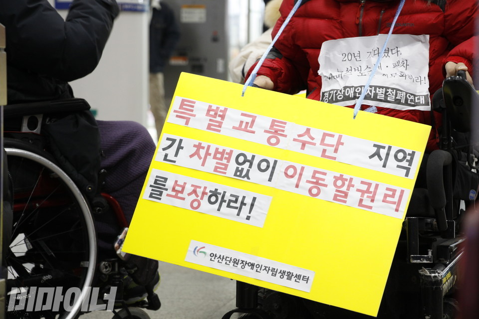 ‘특별교통수단 지역 간 차별없이 이동할 권리를 보장하라!’라는 피켓을 목에 걸고 있는 활동가. 사진 허현덕