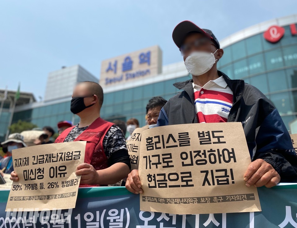 홈리스행동 등은 2020년 5월 11일, 서울역 광장 앞에서 홈리스에 대한 긴급재난지원금 보장을 촉구하는 긴급 기자회견을 열었다. 활동가들이 ‘홈리스를 별도 가구로 인정하여 현금으로 지급!’, ‘지자체 긴급재난지원금 미신청 이유 50% 거주불명 등, 26% 방법 몰라’라고 적힌 피켓을 들고 있다. 사진 이가연