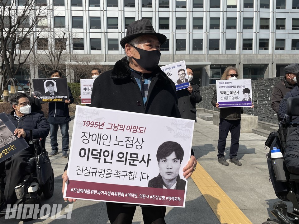 이덕인 열사의 아버지 이기주 씨가 '1995년 그날의 아암도! 장애인 노점상 이덕인 의문사 진실규명을 촉구합니다'라고 적힌 피켓을 들고 있다. 사진 하민지