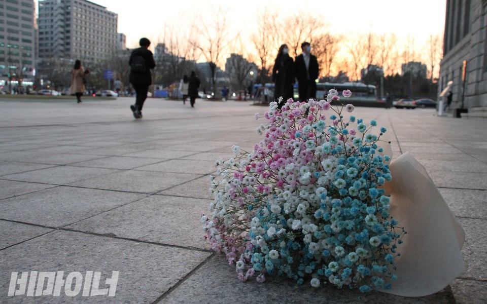 지난 4일, 변희수 하사를 추모하는 시민들은 트랜스젠더를 상징하는 흰색, 분홍색, 하늘색의 조합으로 추모 꽃다발을 준비했다. 꽃다발이 서울시청 앞 광장에 놓였고 그 뒤로 다른 시민들이 퇴근길 발걸음을 옮기고 있다. 사진 하민지