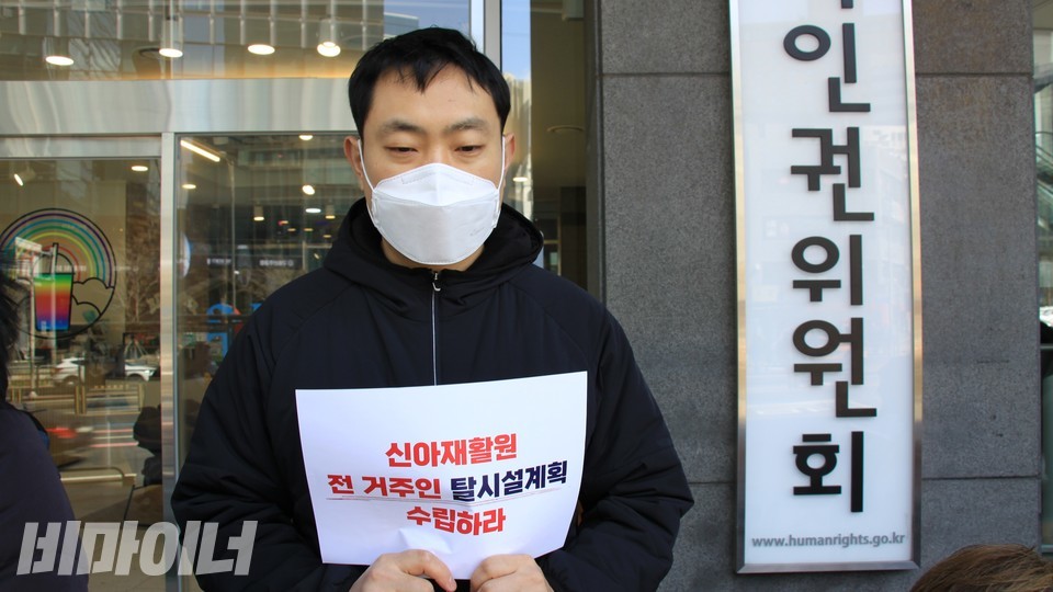 한 활동가가 인권위 간판 앞에서 '신아재활원 전 거주인 탈시설계획 수립하라'라는 피켓을 들고 기자회견에 참여하고 있다. 사진 하민지