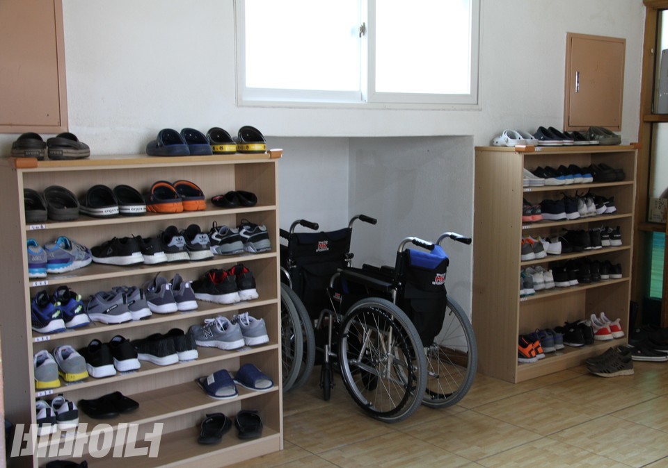 두 개 유닛 사이에 있는 신발장과 휠체어. 신발이 빼곡하게 놓여 있다. 사진 허현덕