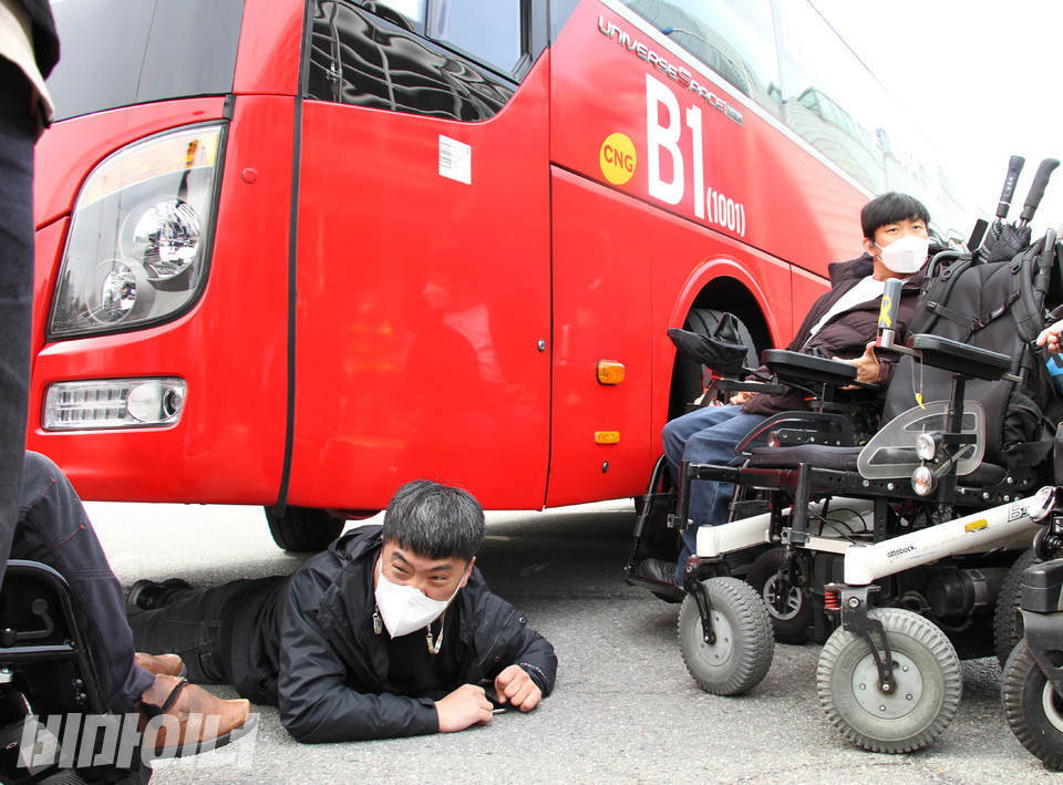 또 다른 장애인 활동가도 장애인은 탈 수 없는 B1버스를 규탄하며 이를 저지하기 위해 버스 밑으로 들어갔다. 사진 강혜민